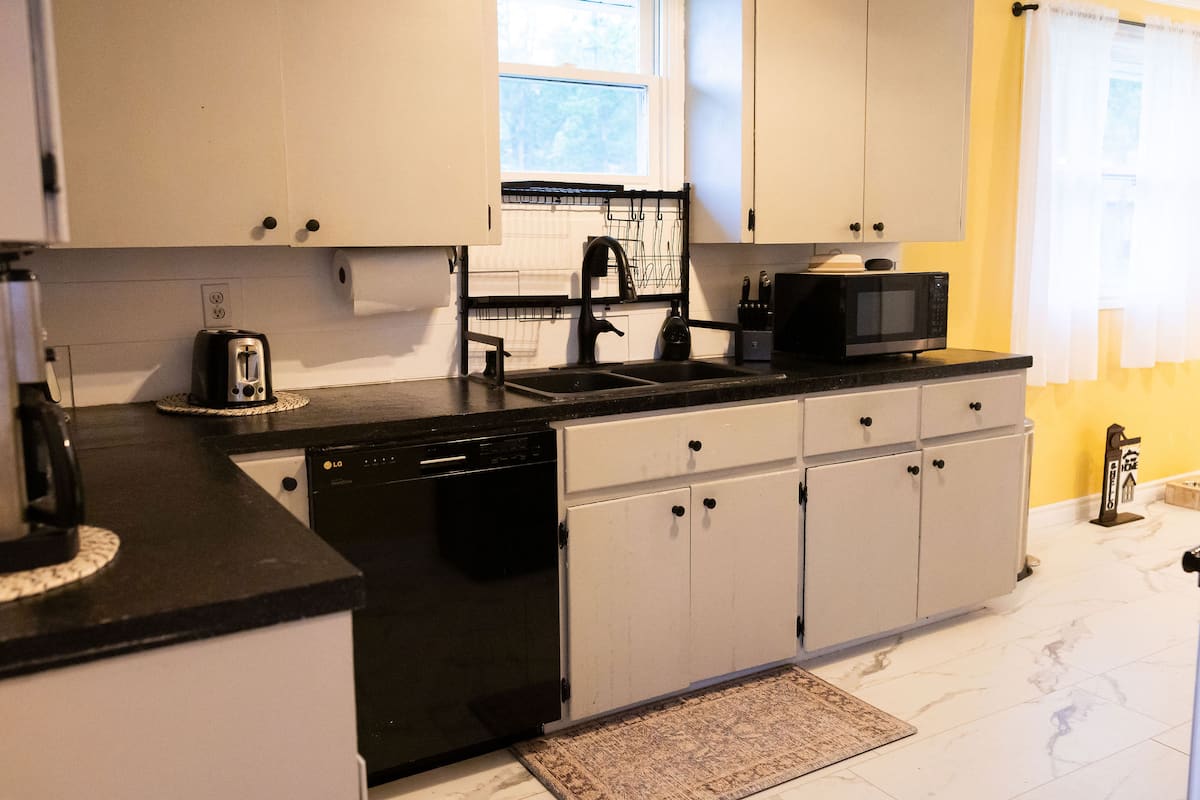 The kitchen, with white cabinets and black counters