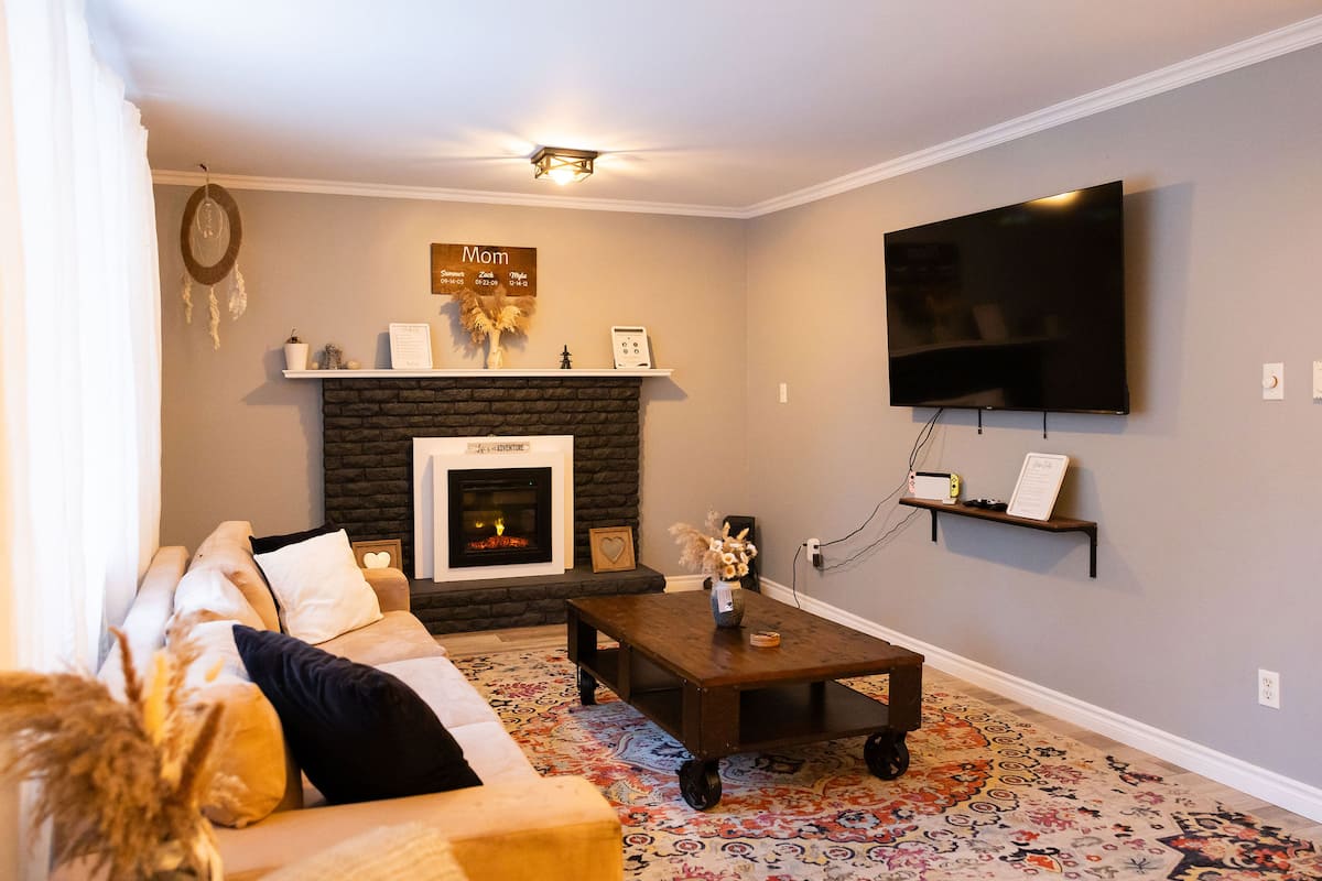 The living room, with a sofa, a fireplace and a TV on the wall