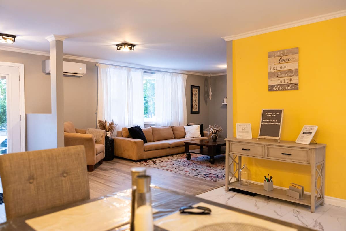 The open living and dining area, with a yellow wall and the kitchen beyond